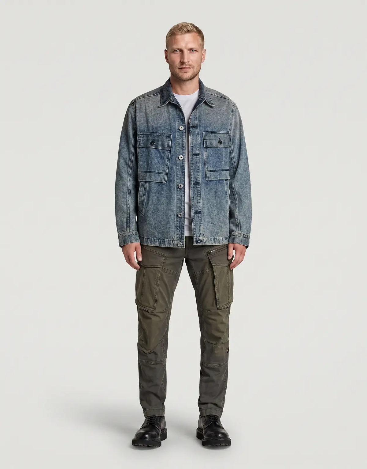 Male model wearing a faded blue denim jacket and olive green G-Star RAW Rovic Zip 3D Regular Tapered Cargo Vintage Dust