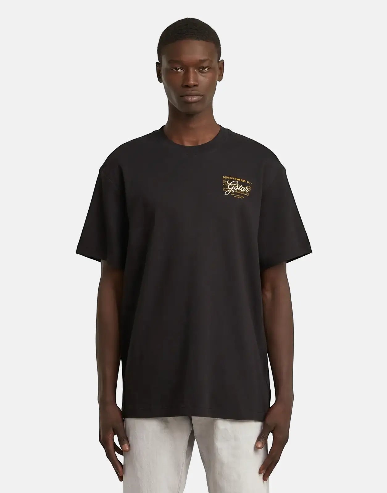 G-Star RAW Script Black T-Shirt worn by a male model, showcasing the short-sleeved top with a yellow and white chest logo.