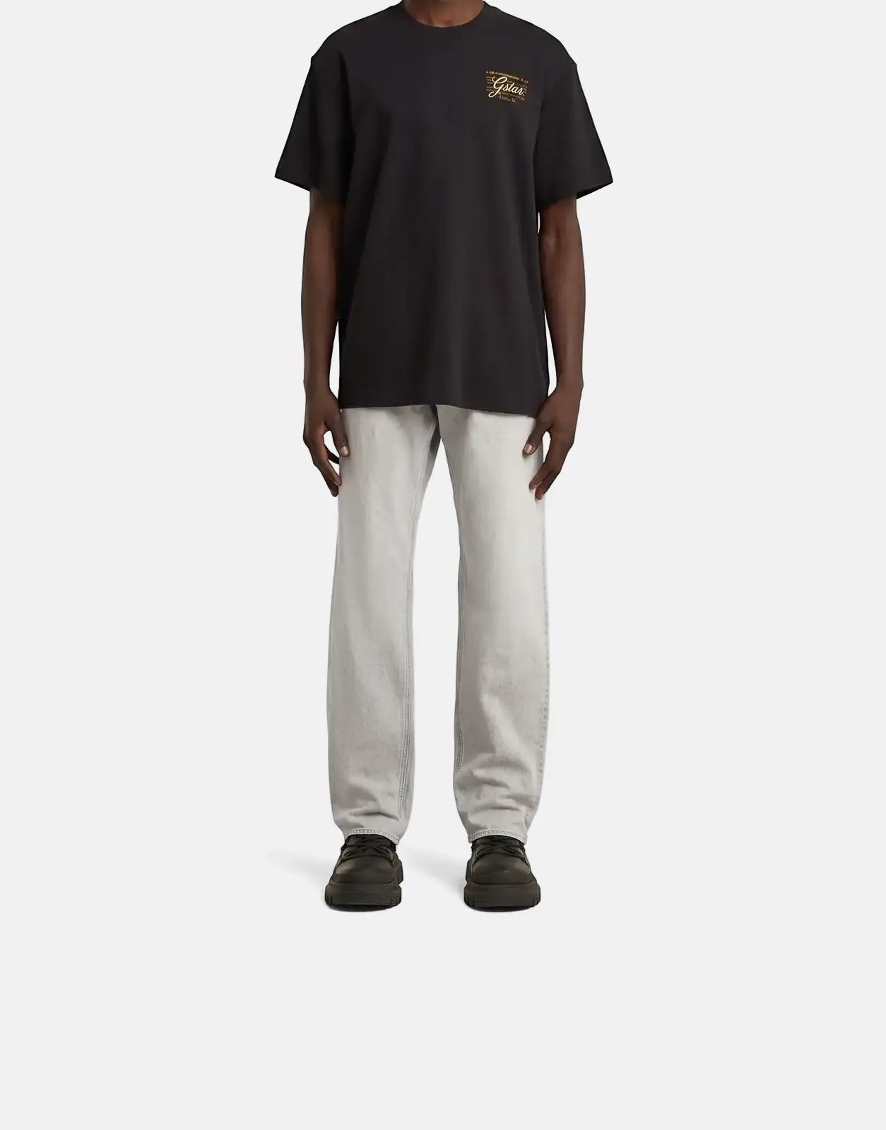 G-Star RAW Script Black T-Shirt worn by a male model, paired with light grey jeans and black shoes, standing front-facing.