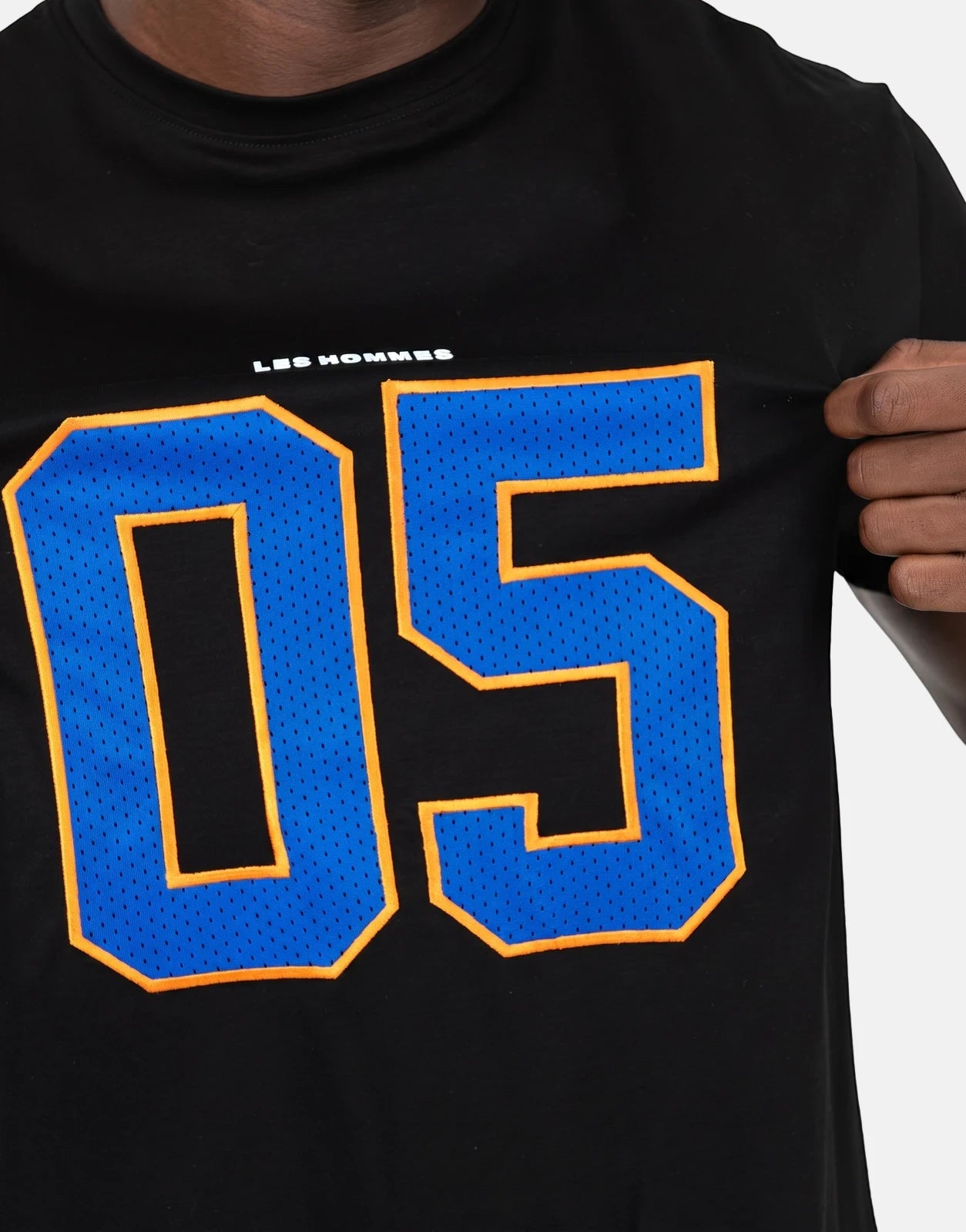 Close-up of Les Hommes 05 Black T-Shirt featuring a large blue and orange '05' graphic and 'LES HOMMES' text.