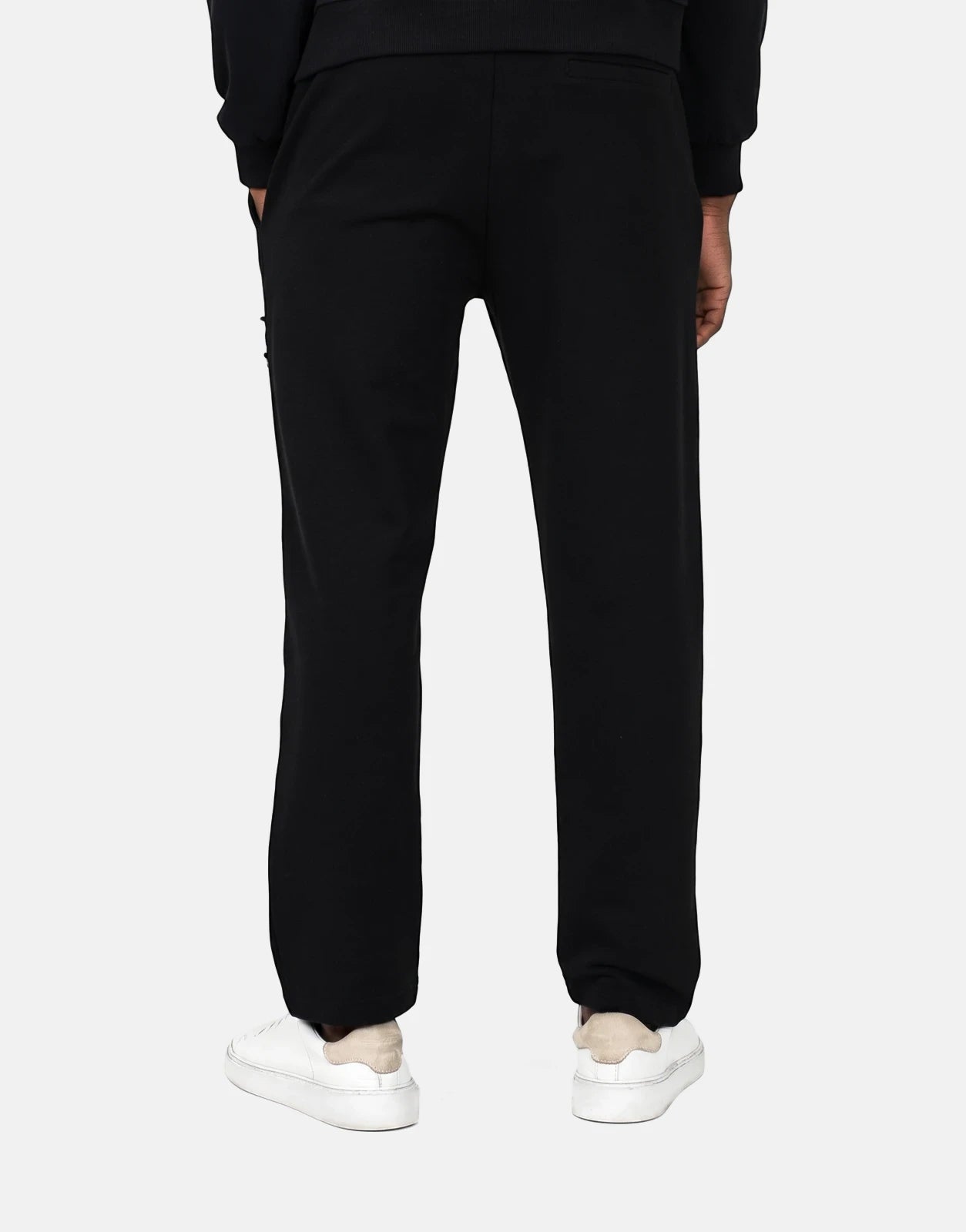 Les Hommes black jogger pants on a model from the back, showcasing the comfortable fit and casual style with white sneakers.
