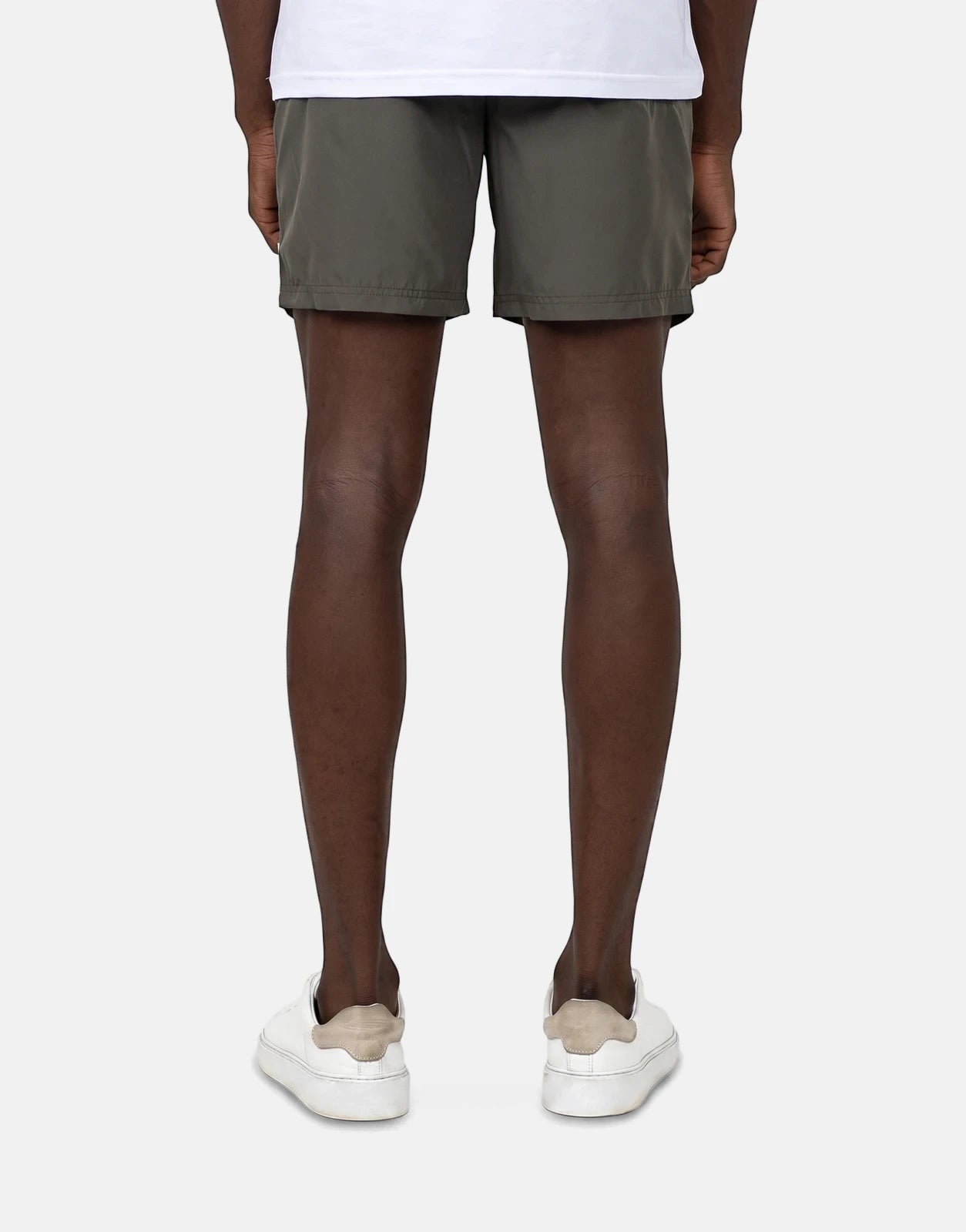 Les Hommes Colour Green Swim Shorts on a male model, seen from the back, paired with white sneakers.