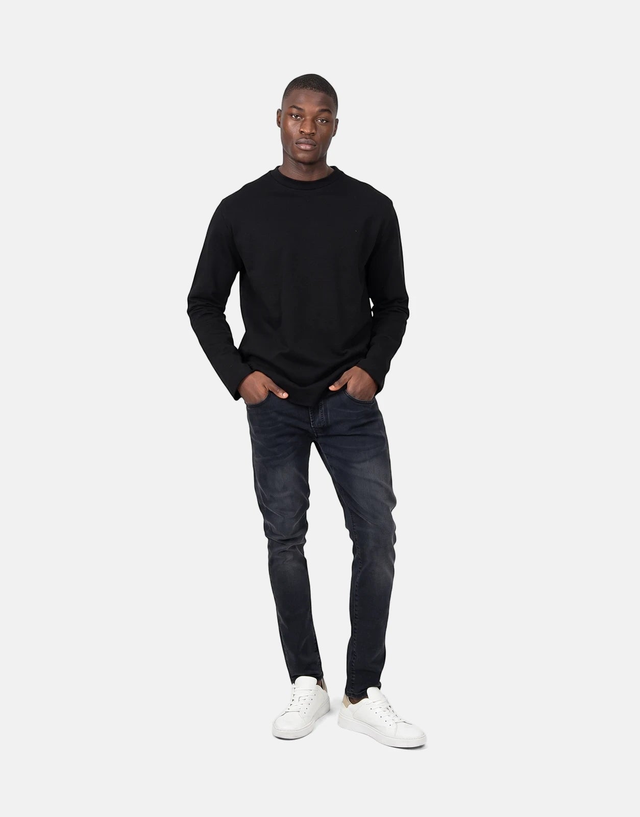 A black long-sleeved Les Hommes Dragonfly sweatshirt on a male model paired with dark jeans and white sneakers.