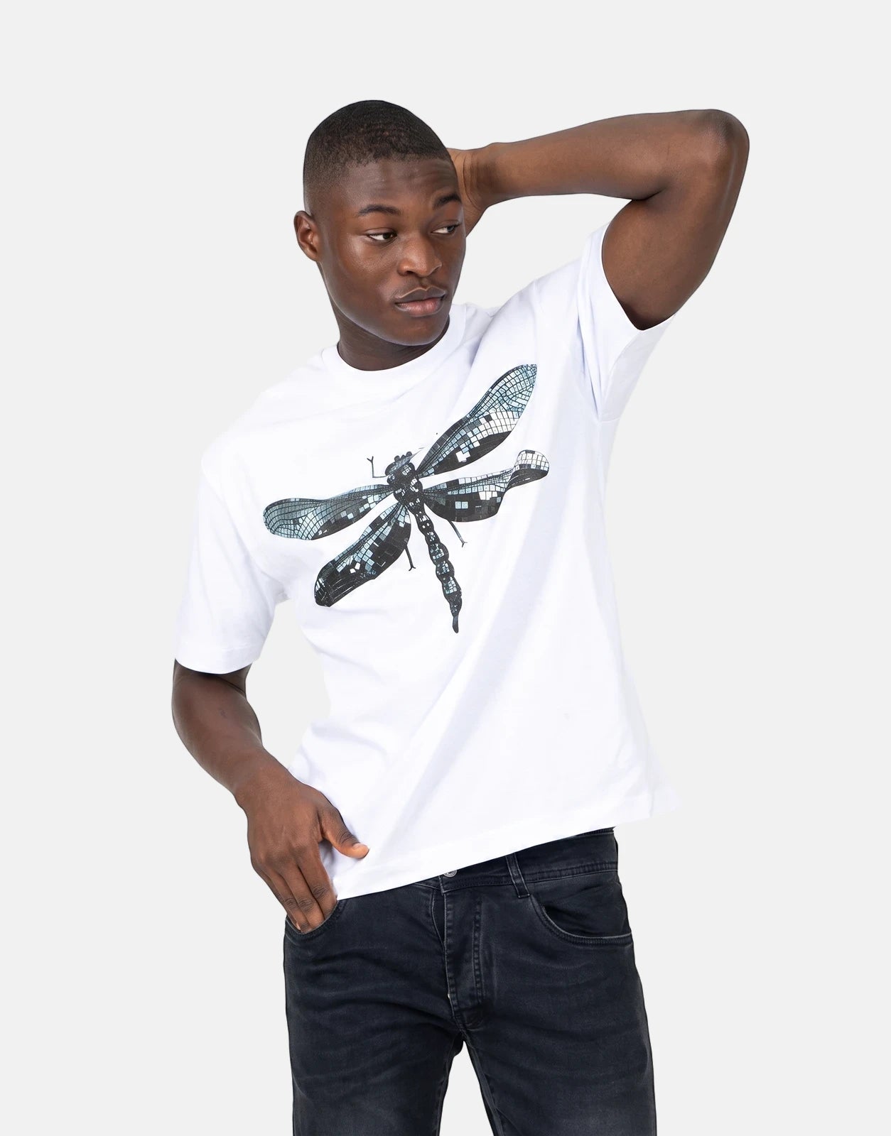 A male model wearing a Les Hommes white short-sleeve t-shirt with a black and blue mosaic-style dragonfly print, paired with