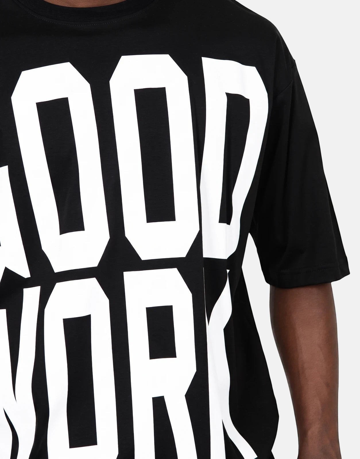 Close-up of a person wearing a black Les Hommes Good Work t-shirt with large white lettering.