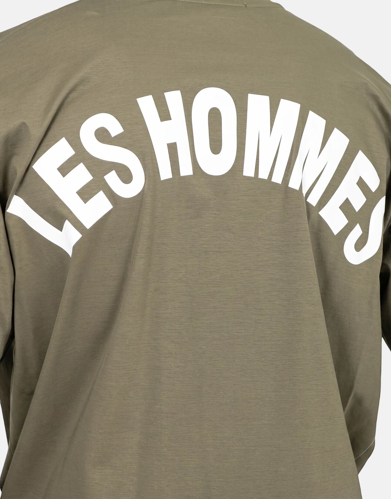 Back view of a men's Les Hommes olive green t-shirt featuring a large arched white 'LES HOMMES' logo printed across the