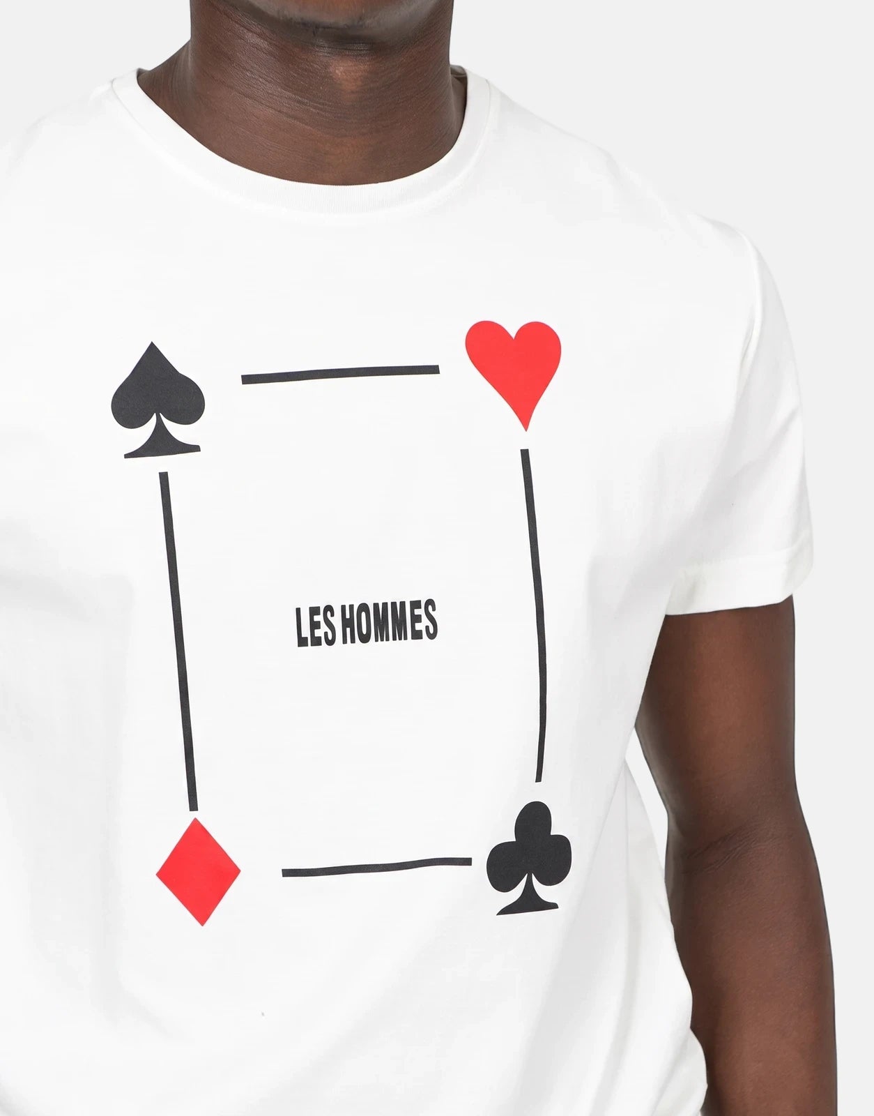 Les Hommes Poker Print White T-Shirt worn by a model, featuring black spade, red heart, red diamond, and black club graphics.