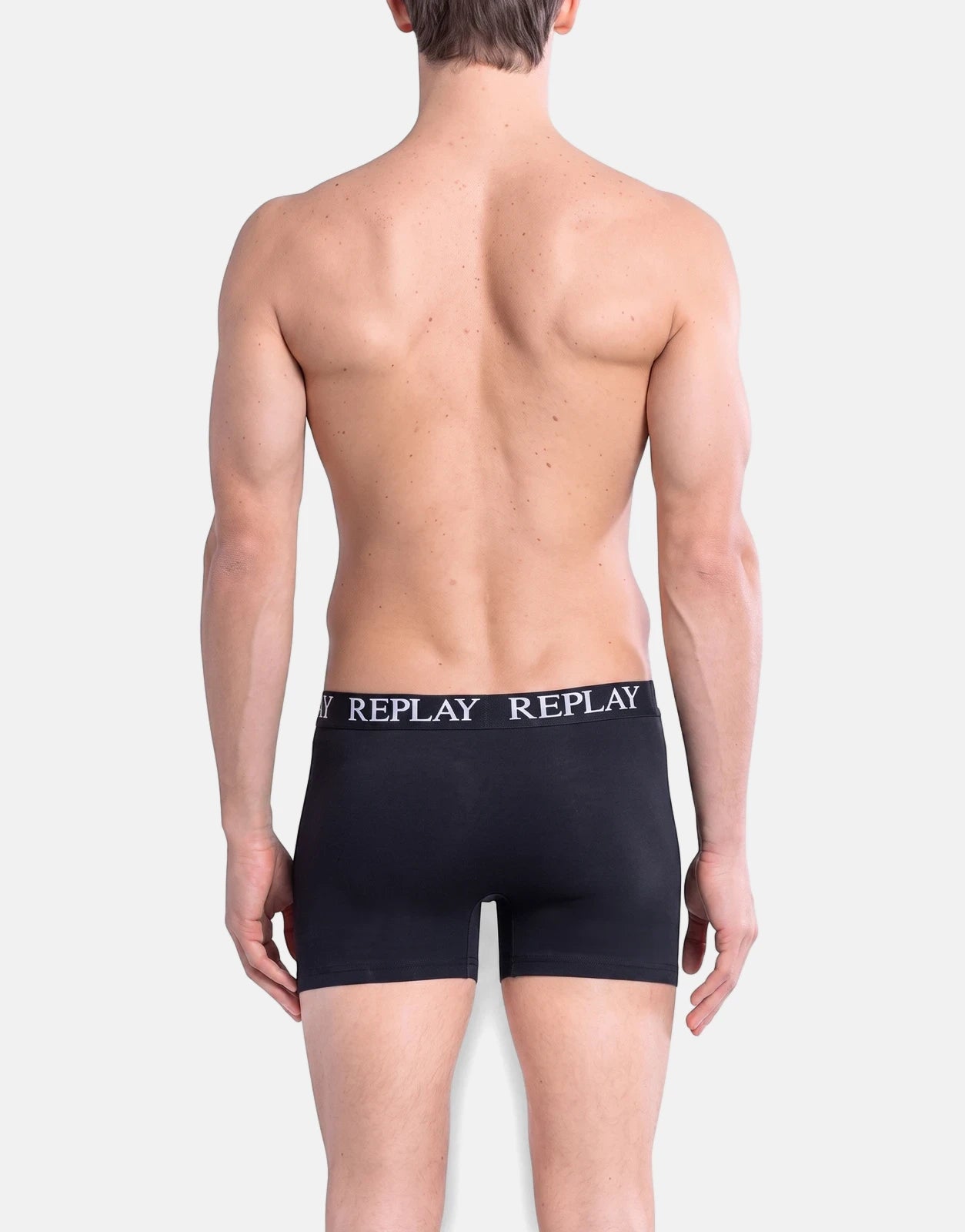 Male model wearing black Replay boxer briefs, seen from the back. Focus on the fit and branding.
