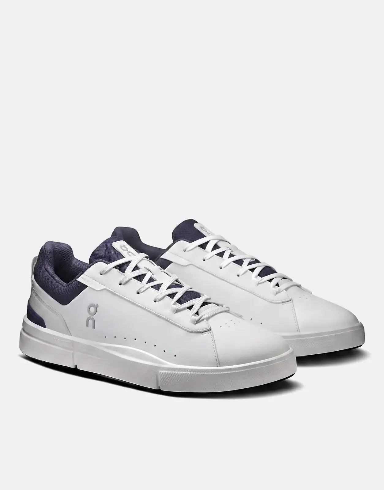 A pair of On Men's The Roger Advantage sneakers in white and midnight blue, with white laces and silver accents, from a side