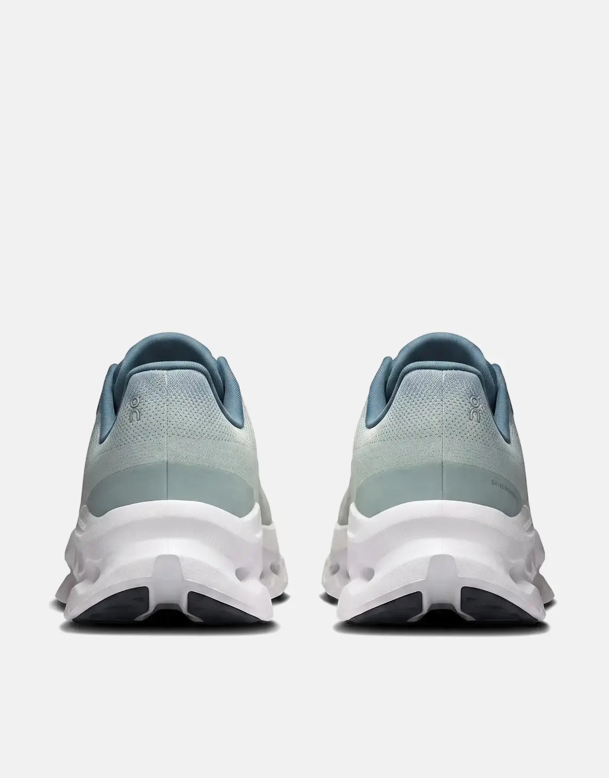 Back view of On Men's Cloudtilt Tide Mineral sneakers. The running shoes are light blue and mint green with white soles.