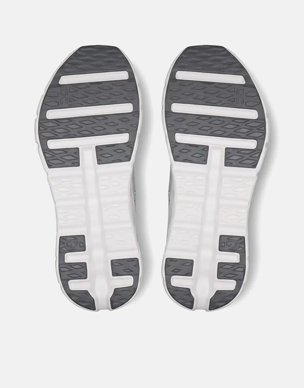 Soles of two On Men's Cloudtilt Tide Mineral sneakers in white with dark gray tread, viewed from below.