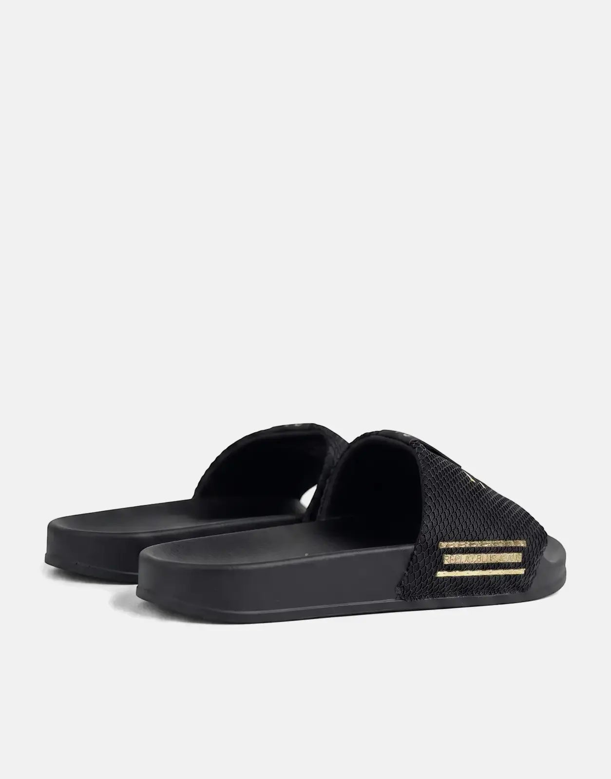 A pair of black Replay Up Trap slides featuring gold branding on a textured strap, seen from a low angle.