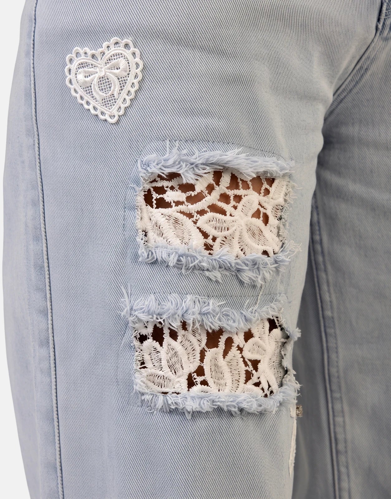 Close-up of Sissy Boy Kiera Wide Leg Light Vintage Jeans in light blue, featuring ripped details with white lace patches and