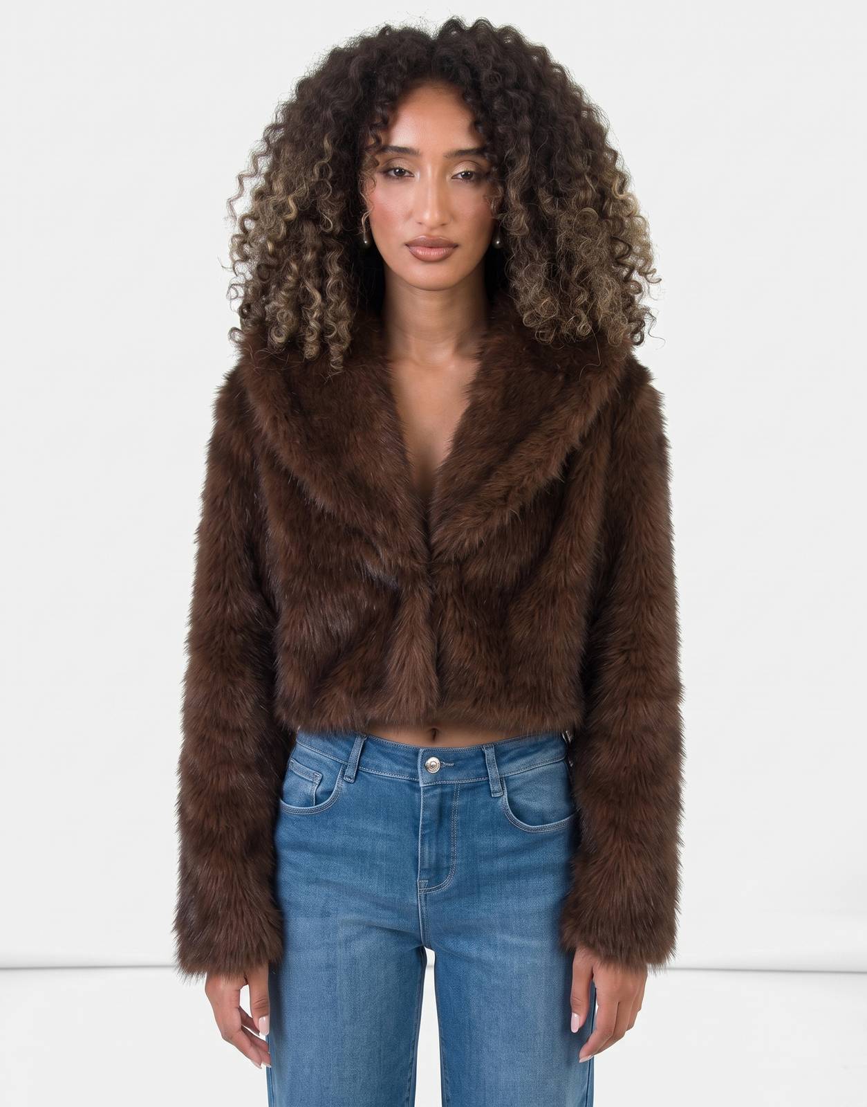 A female model wears a Sissy Boy Needing Me Faux Fur Cropped Brown Jacket, showcasing its luxurious texture and stylish cut.
