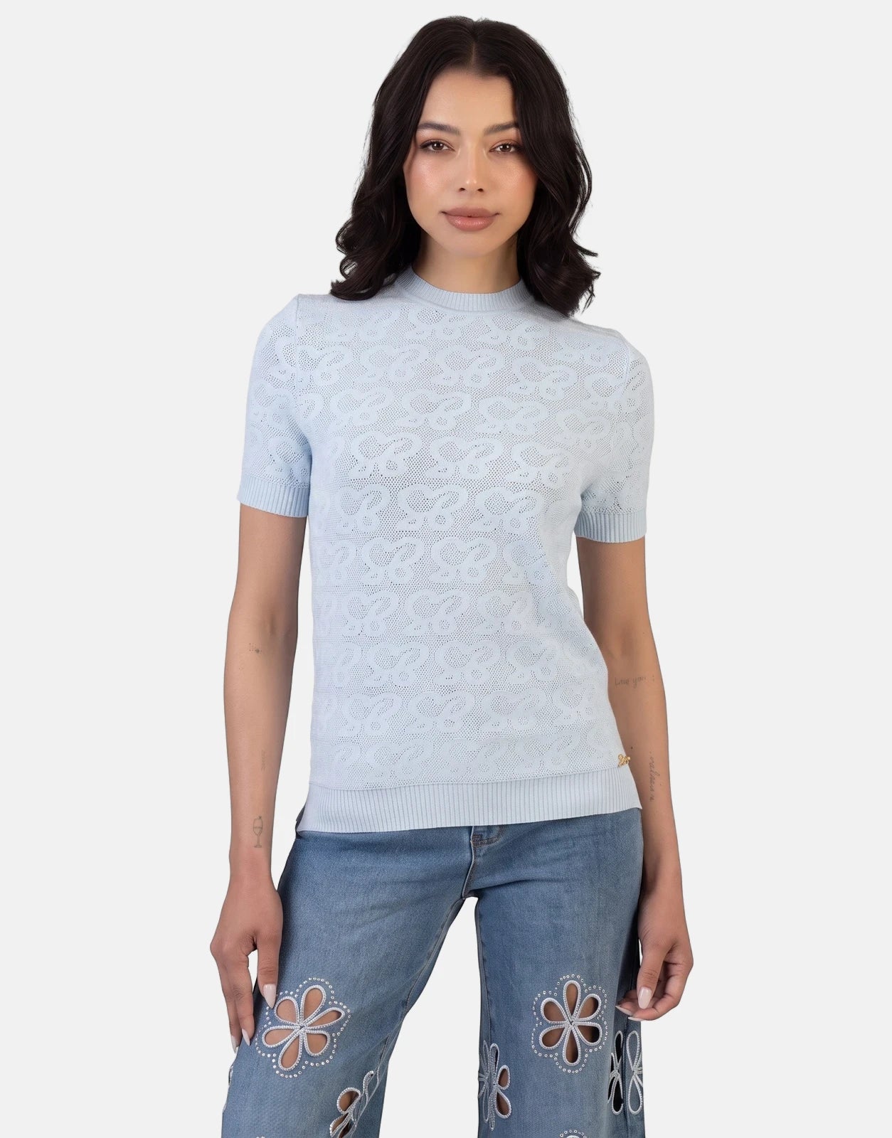 Woman wearing a Sissy Boy Next Level Pale Blue Knit Top with intricate open-knit pattern and short sleeves, paired with