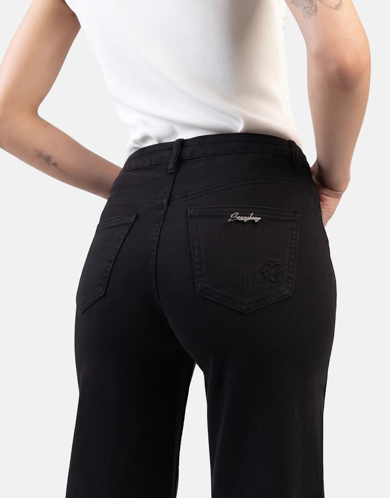 Rear view of a model wearing Sissy Boy Nollene wide leg black high waist jeans, showcasing the back pockets and branding.
