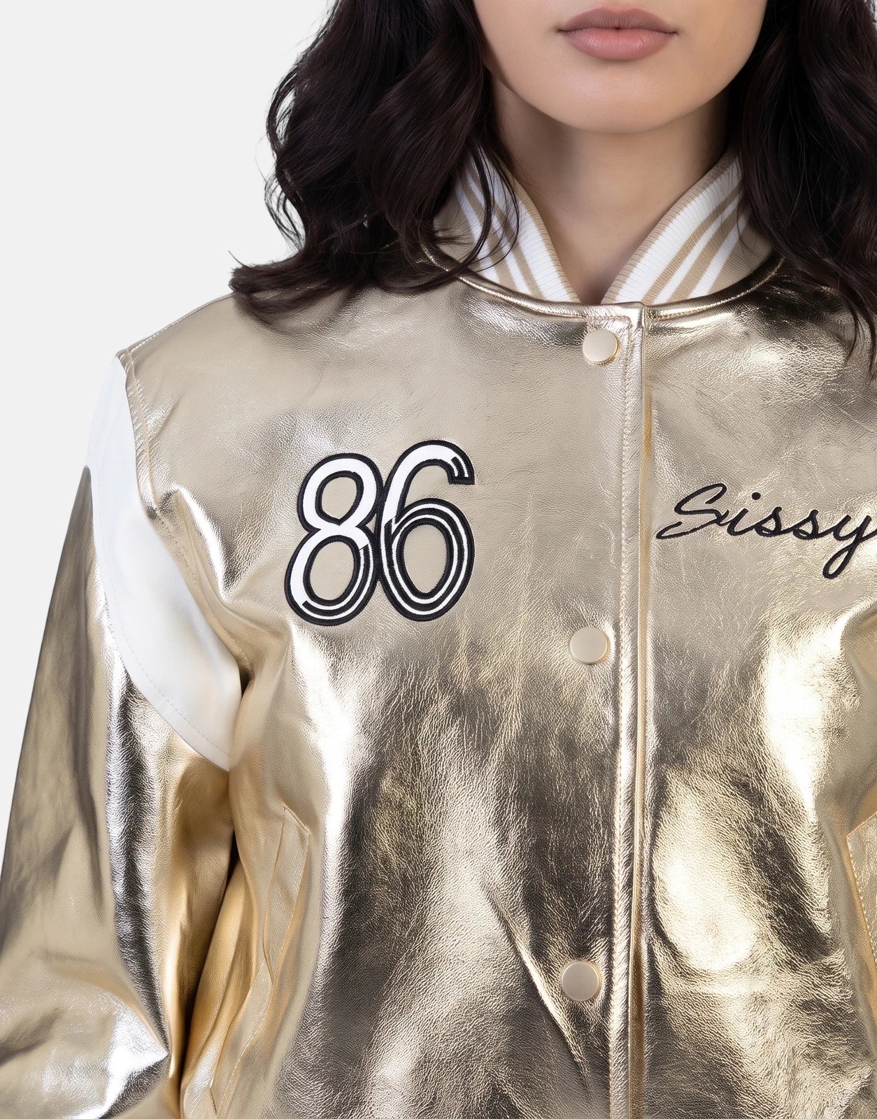 Close-up of a woman wearing a Sissy Boy Take It Easy Gold Bomber Jacket with '86' embroidered, metallic gold and white