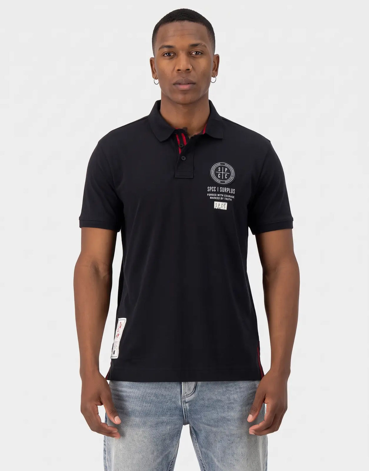 Front view of a men's black SPCC Roarke polo shirt with a white circular logo on the chest and red accents, worn by a model.