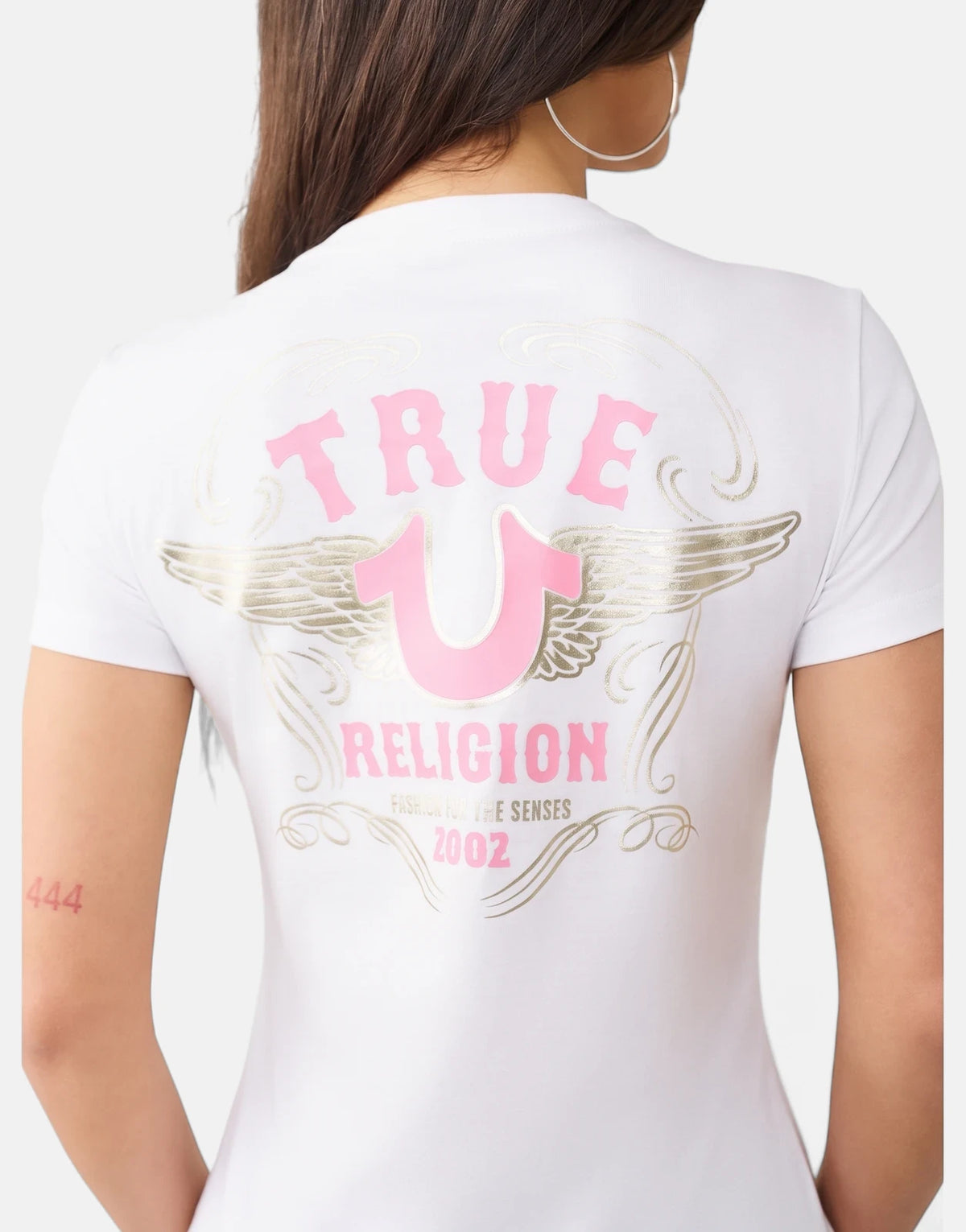 Women's white True Religion HS Wing T-Shirt featuring a prominent pink and gold graphic logo on the back.